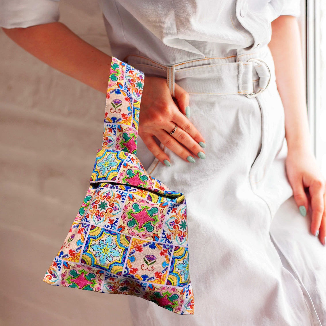 Woman carrying hands-free Japanese knot bag wristlet made from Kelly Ser tile print canvas